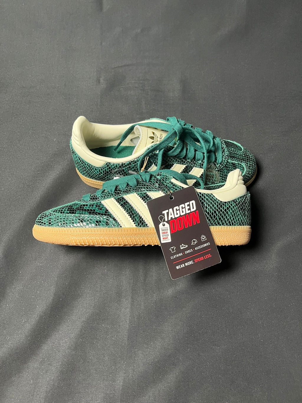 Green Adidas sneakers with a visible tag on a gray background