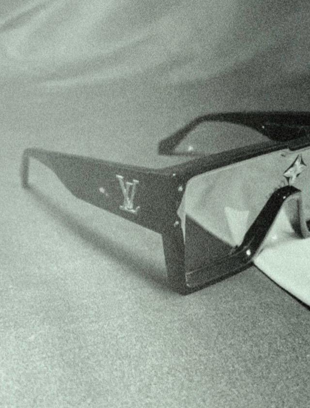 Black sunglasses with a brand logo on a light gray background