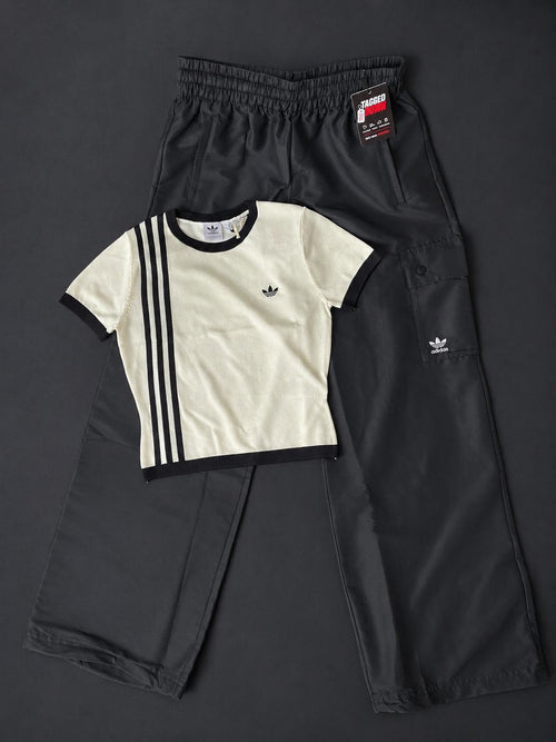 Black Adidas tracksuit with a white shirt featuring three stripes on a dark background