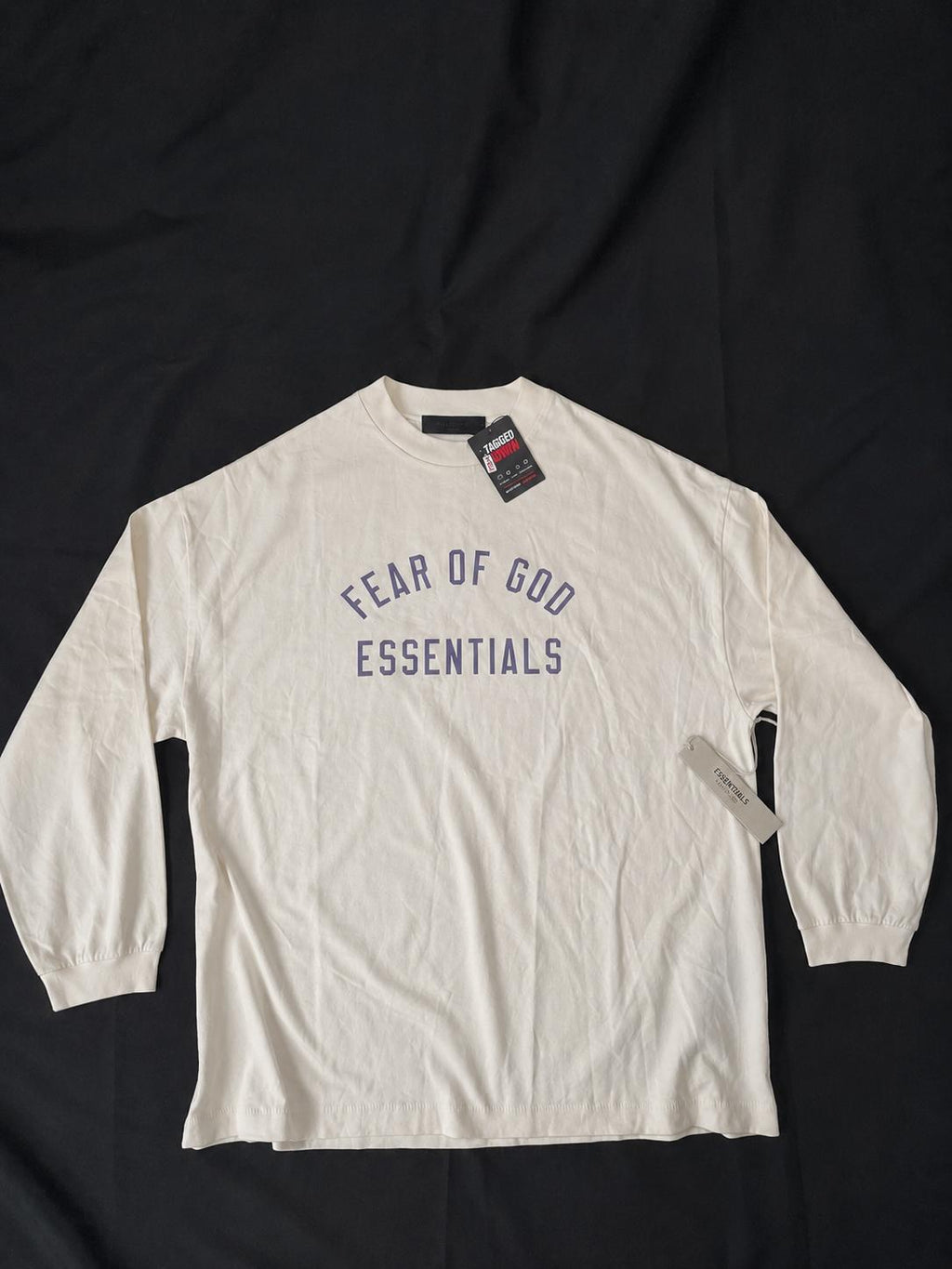 Fear of God Essentials cream long sleeve T-shirt in size XS, brand new with tags. Features purple Essentials front logo print on a premium heavyweight cotton design.