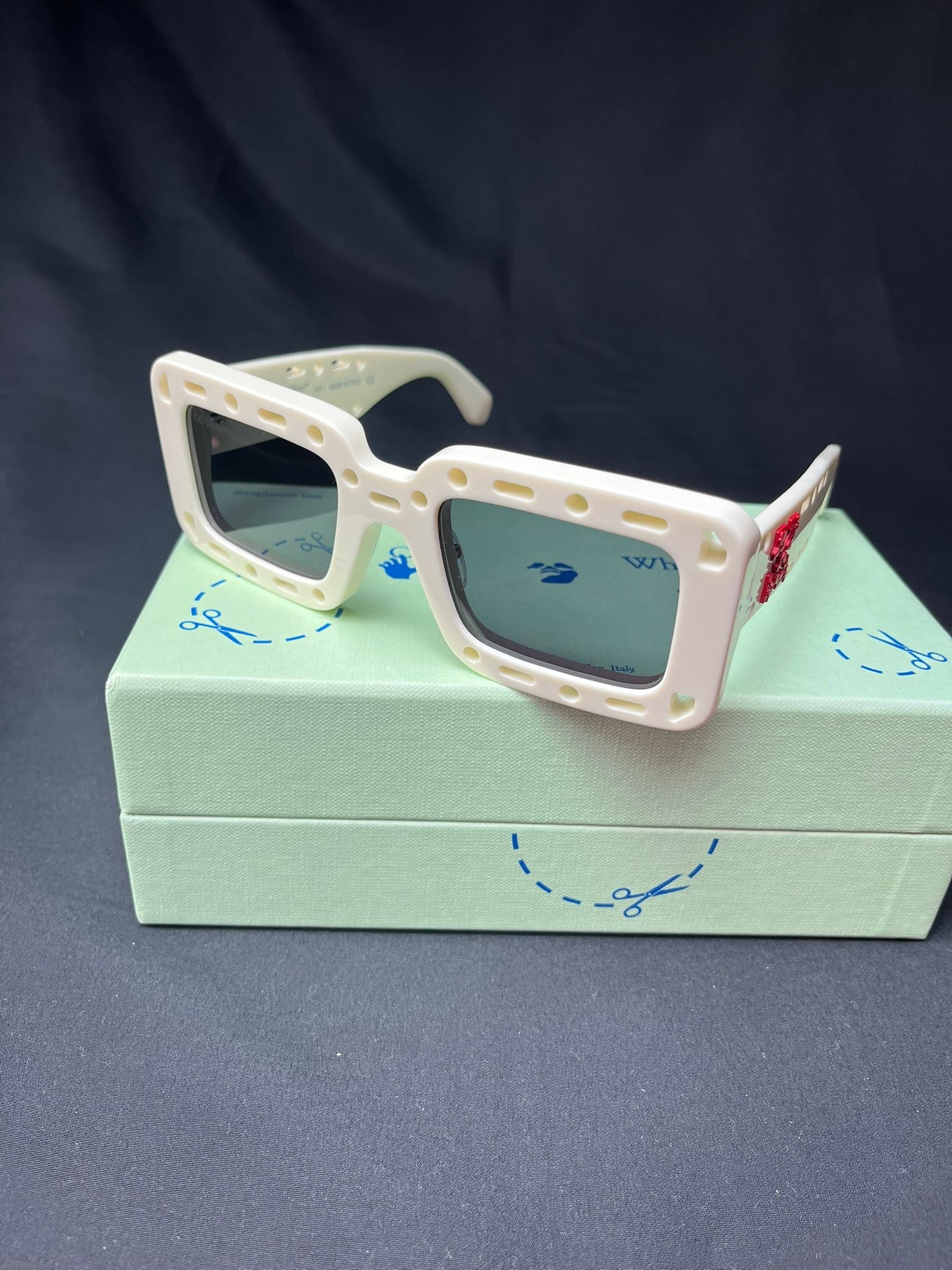 Off-White™ white designer sunglasses with red Arrow logo, dark lenses and original presentation box.